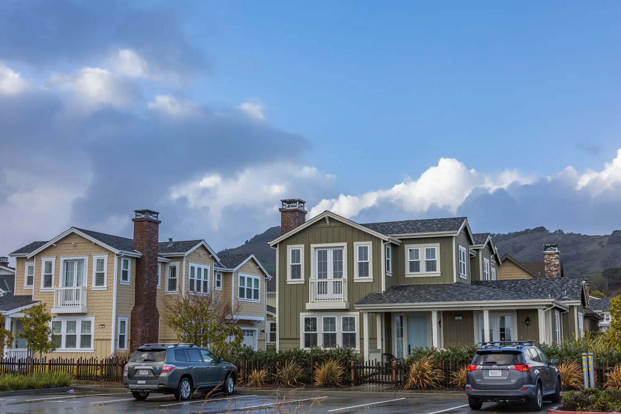 A row of two-storey houses on a suburban street under broken cloud